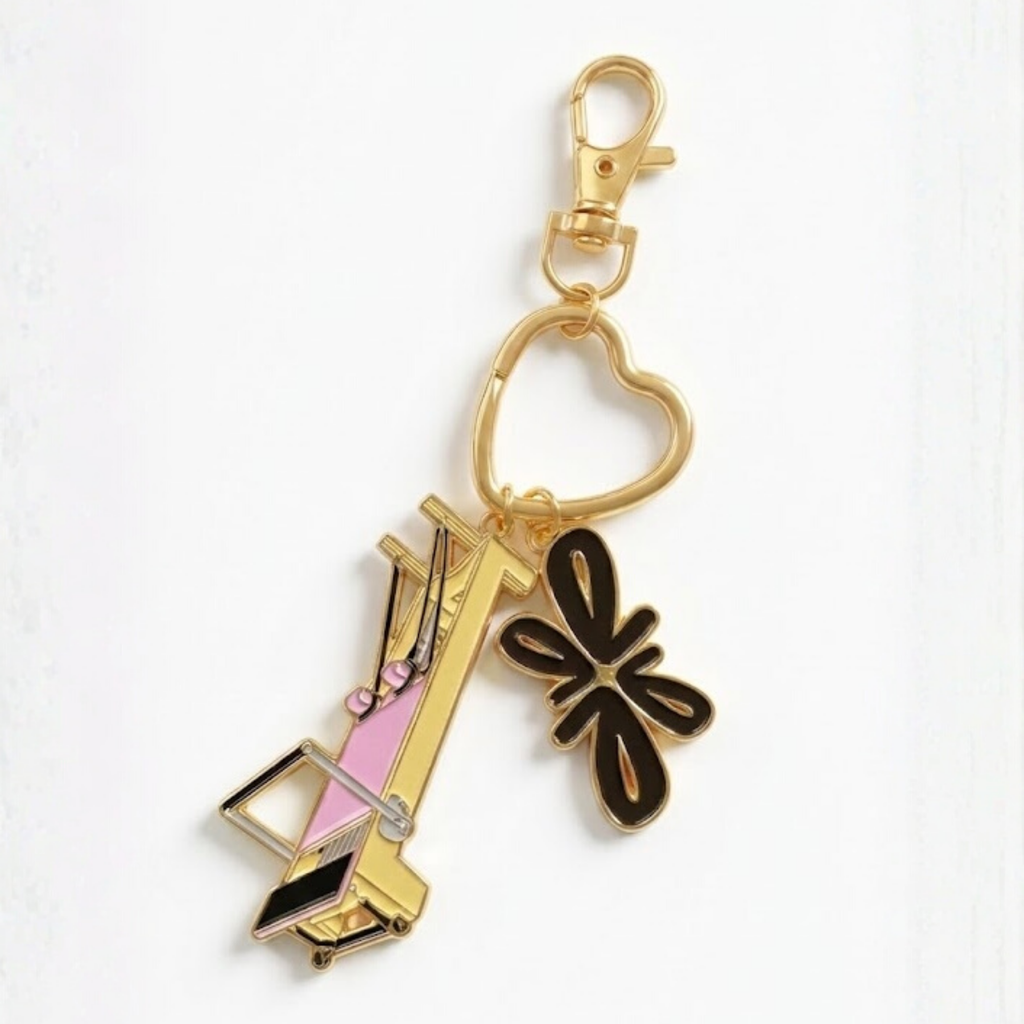 Tuelles Miniformer Keychain, gold-tone mini Pilates reformer keychain with a high-heel charm